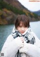 A woman wearing a white coat and a black and white scarf.