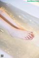 A woman's feet in a bathtub filled with water.