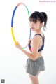 A young woman holding a hula hoop in her hands.