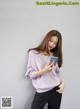 a woman in a purple sweater and black pants holding a cell phone