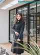 a woman standing in front of a building wearing a black trench coat