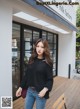 A woman standing in front of a building wearing a black sweater.