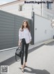 a woman in a white shirt and black pants is walking down the street