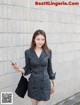 A woman in a black and white striped blazer dress holding a cell phone.