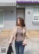 A woman is walking down the street in jeans and a jacket.