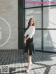 a woman standing in front of a building wearing a white shirt and black skirt