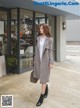 a woman in a gray coat is walking down the street