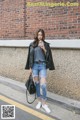 A woman standing on the side of a street holding a drink.