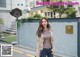 A woman standing in front of a building wearing jeans and a jacket.