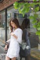 A woman standing in front of a store window holding a handbag.