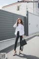 A woman wearing a white and black striped shirt and black pants.