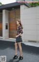 A woman is walking down the street carrying a black bag.