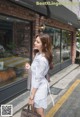 A woman walking down the street carrying a brown bag.