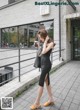 A woman in a black dress is walking down the street.