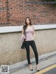 A woman standing in front of a brick wall.