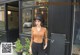 A woman standing in front of a cafe wearing a hat.