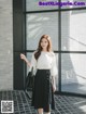 a woman wearing a white shirt and black skirt