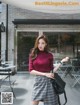 A woman in a red sweater and plaid skirt posing for a picture.