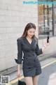 a woman in a black and white striped suit is walking down the street