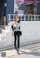 A woman walking down the street in front of a building.