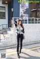 A woman standing in front of a white brick building.