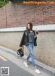 A woman walking down the street holding a drink.