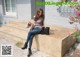 A woman sitting on the steps of a building with a handbag.