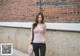 A woman standing in front of a brick wall.