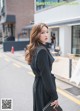 A woman in a black dress is walking down the street.