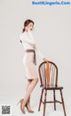 A woman standing next to a wooden chair.