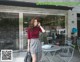 A woman standing in front of a coffee shop talking on a cell phone.