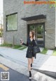 A woman in a black dress is walking down the street.