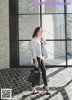 a woman standing in front of a window holding a black bag