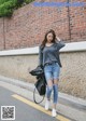 A woman in ripped jeans and a gray shirt is walking down the street.