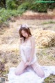 A woman in a white lingerie sitting on a pile of hay.