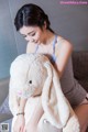 A woman sitting on a couch holding a large stuffed animal.