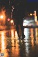 A person standing in the rain at night in the city.