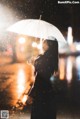 A woman standing in the rain holding an umbrella.