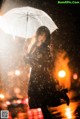 A woman holding an umbrella in the rain at night.