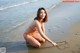 A woman in a bikini sitting on the beach.