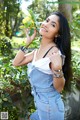 A woman in overalls holding a lemon in her hand.