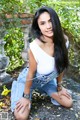 A woman in a white top and blue jeans posing for a picture.