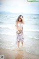 A woman in a white bikini standing in the ocean.