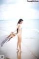 A woman in a white bikini standing on a beach.