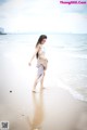 A woman walking on a beach next to the ocean.