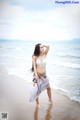 A woman in a white bikini standing on the beach.