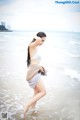 A woman in a white bikini standing in the ocean.