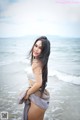 A woman in a white bikini standing in the ocean.