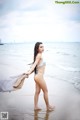 A woman in a white bikini standing on a beach.