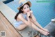 A woman in a straw hat sitting by a swimming pool.